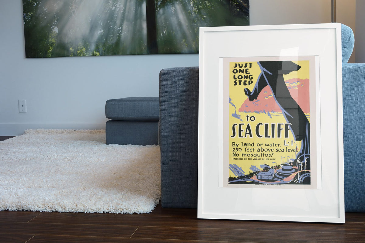 Just One Long Step to Sea Cliff poster leaning beside a blue sofa