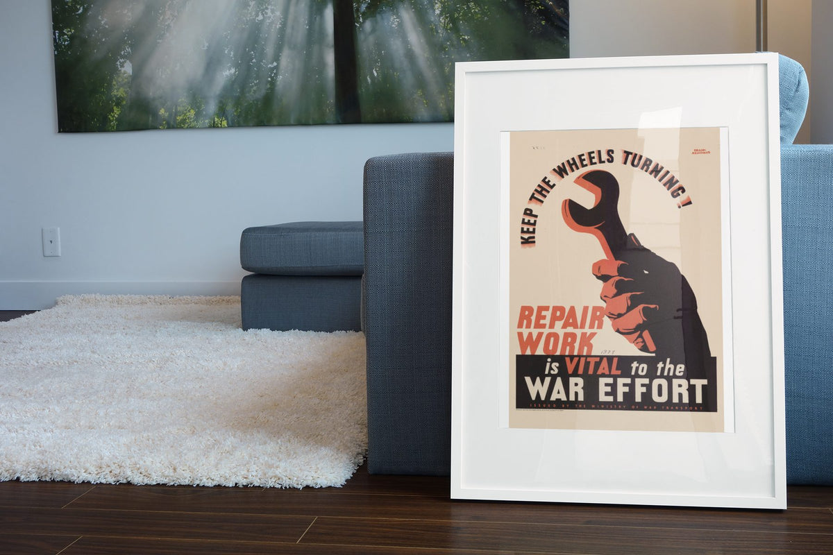 Keep the Wheels Turning Repair Work Is Vital poster leaning beside a blue sofa