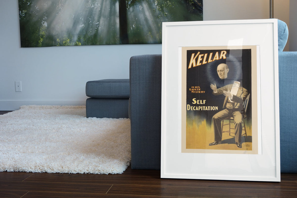 Kellar Self Decapitation poster leaning beside a blue sofa