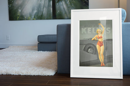 Kelly-Springfield Tires Pin-Up poster in a white frame leaning beside a blue sofa
