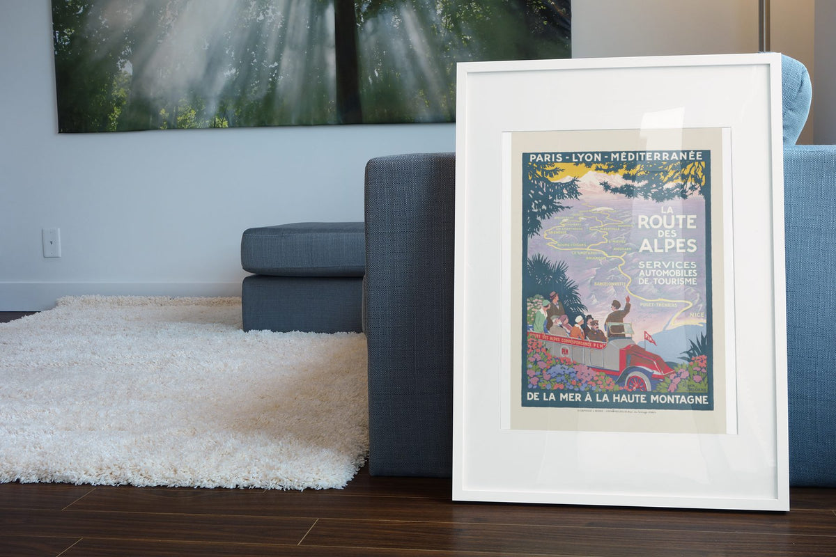 La Route des Alpes poster leaning beside a blue sofa