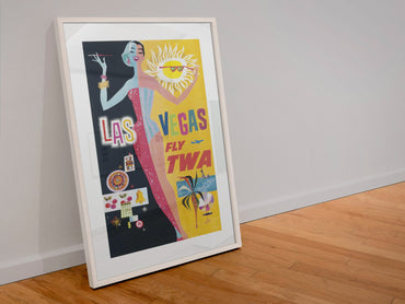 Las Vegas Fly TWA Showgirl poster in a white frame leaning against a wall