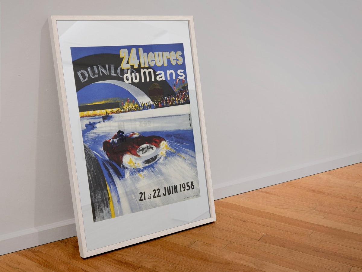 24 Heures du Mans 1958 poster in a white frame leaning against a wall