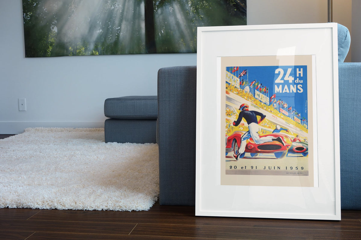 24 Heures du Mans 1959 poster in a white frame leaning beside a blue sofa