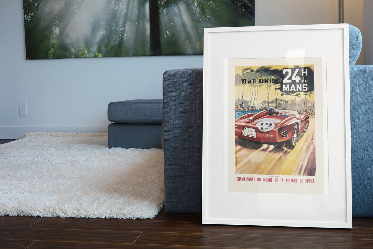 24 Heures du Mans 1961 poster in a white frame leaning beside a blue sofa