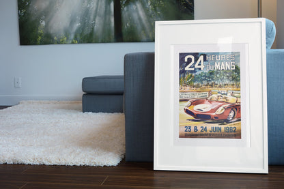 24 Heures du Mans 1962 poster in a white frame leaning beside a blue sofa
