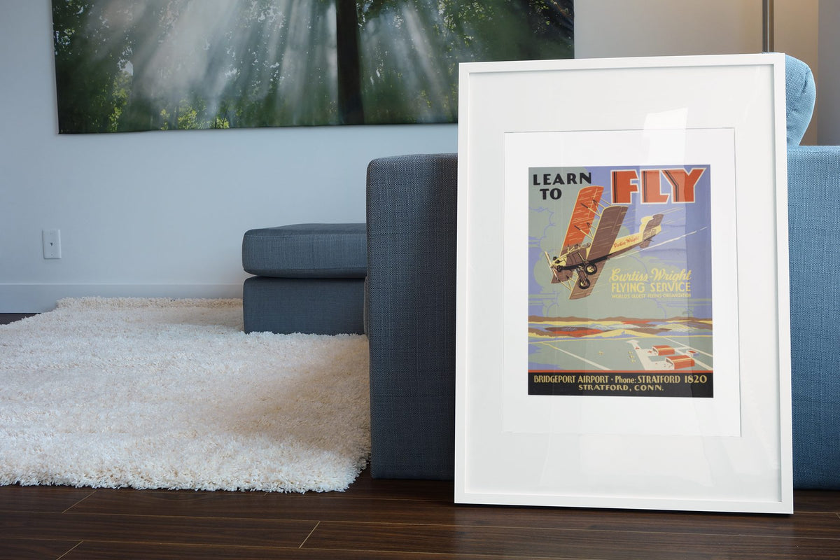 Learn to Fly Curtiss Wright poster leaning beside a blue sofa
