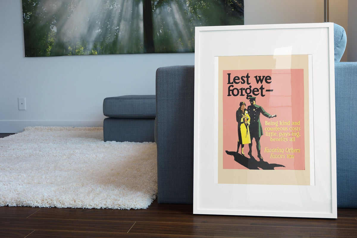 Lest We Forget poster in a white frame leaning beside a blue sofa