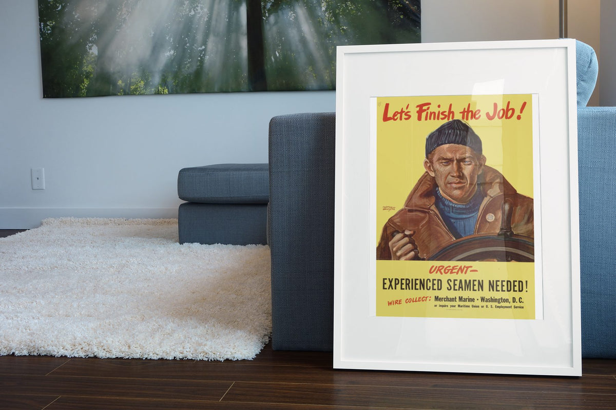 Lets Finish the Job Merchant Marine poster leaning beside a blue sofa