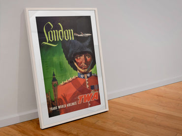 London Fly TWA Royal Guard poster in a white frame leaning against a wall