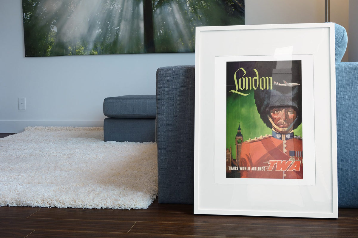 London Fly TWA Royal Guard poster leaning beside a blue sofa