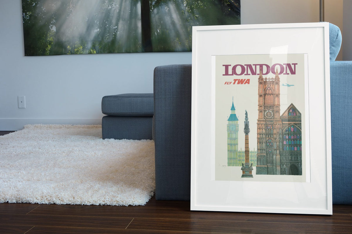 London Fly TWA poster leaning beside a blue sofa
