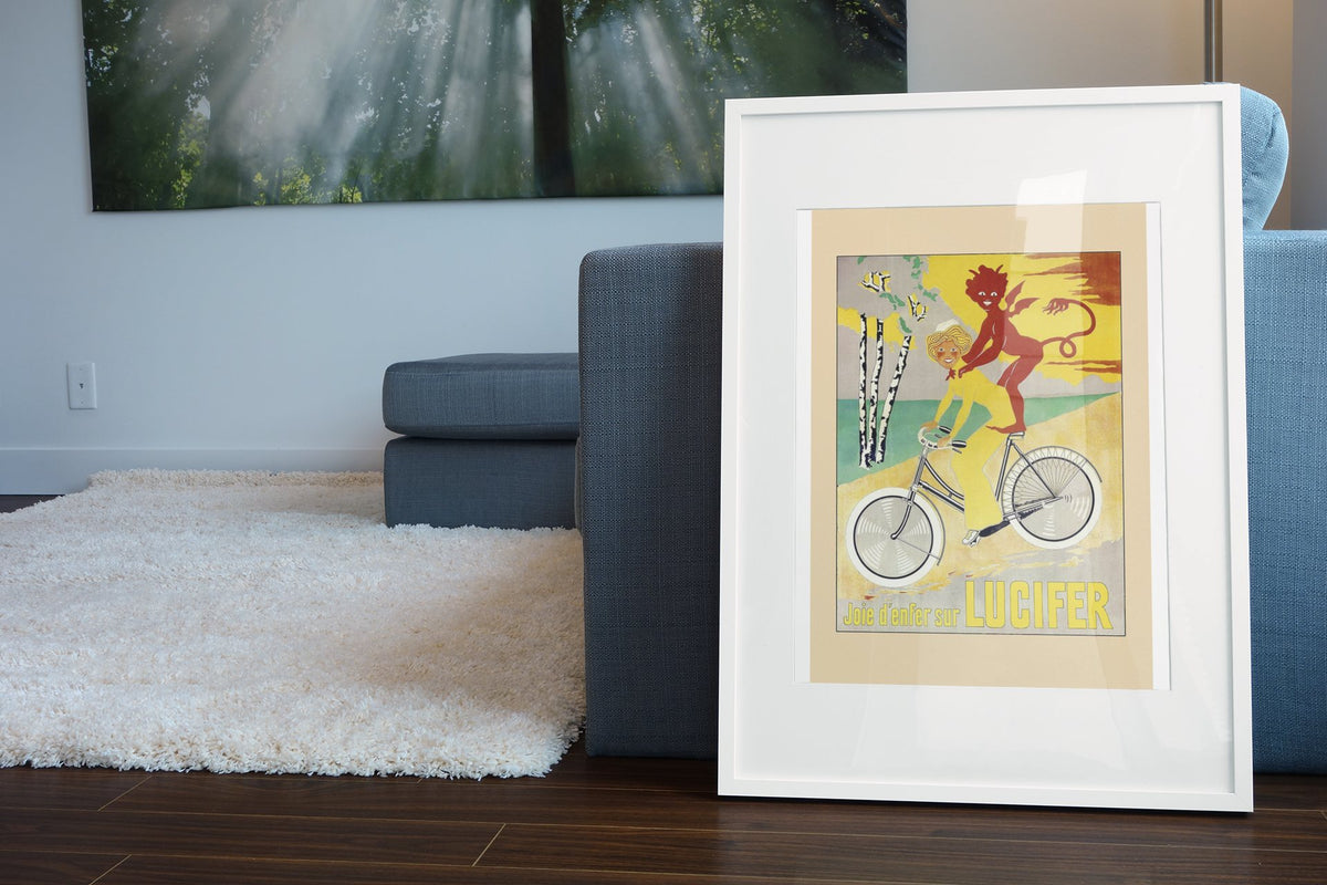 Lucifer Cycles Joie d Enfer poster leaning beside a blue sofa