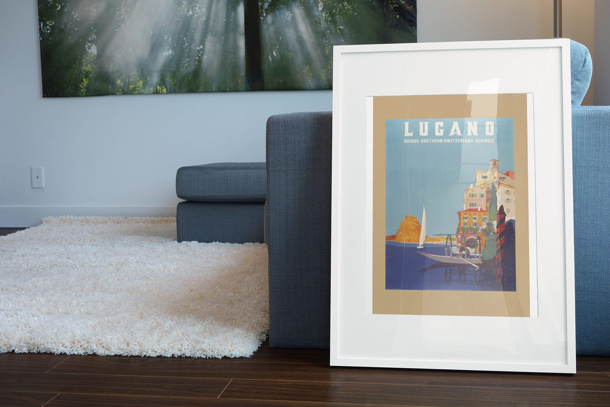 Lugano Southern Switzerland poster leaning beside a blue sofa
