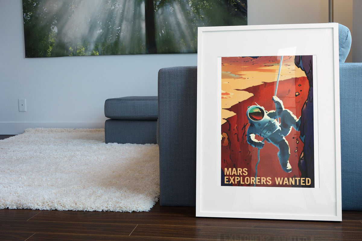 Mars Explorers Wanted poster in a white frame leaning beside a blue sofa