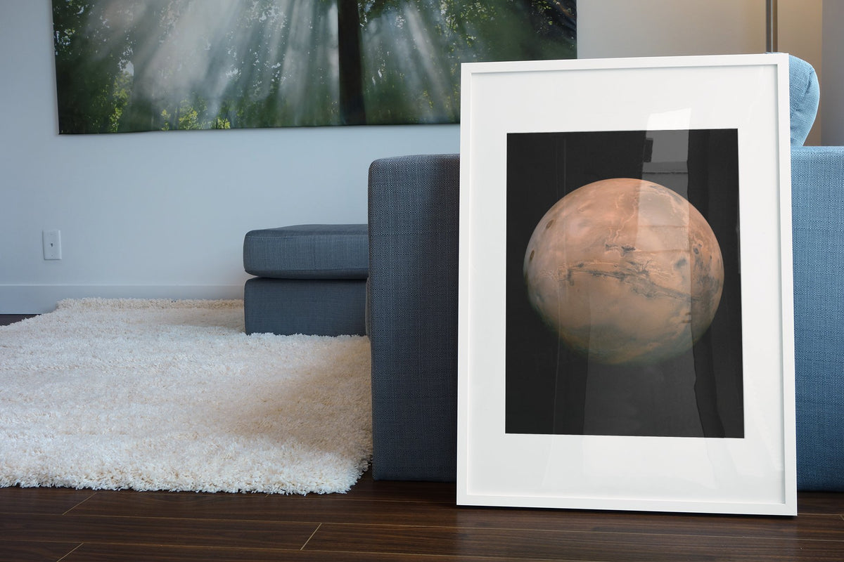 Mars with Valles Marineris poster in a white frame leaning beside a blue sofa