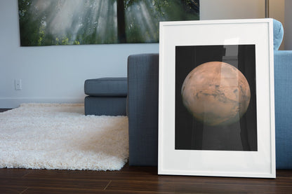 Mars with Valles Marineris poster in a white frame leaning beside a blue sofa