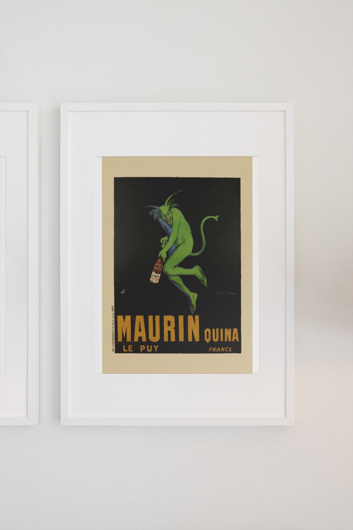 Maurin Quina 1906 green devil by Cappiello poster in a white frame on a light wall
