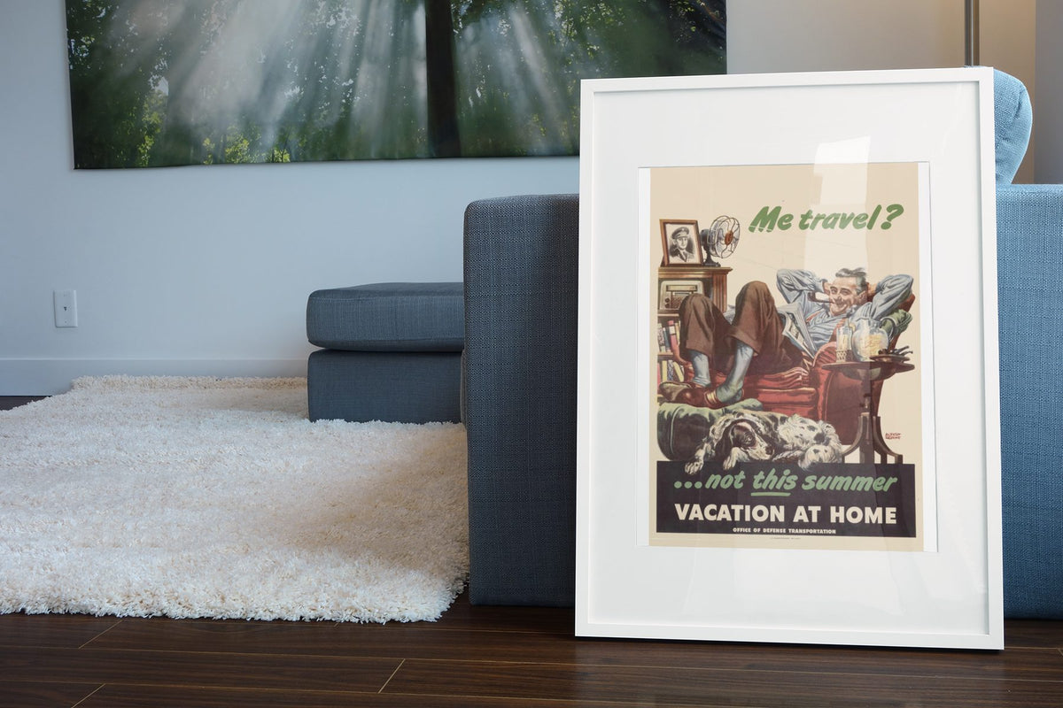 Me Travel Not This Summer Vacation at Home poster leaning beside a blue sofa
