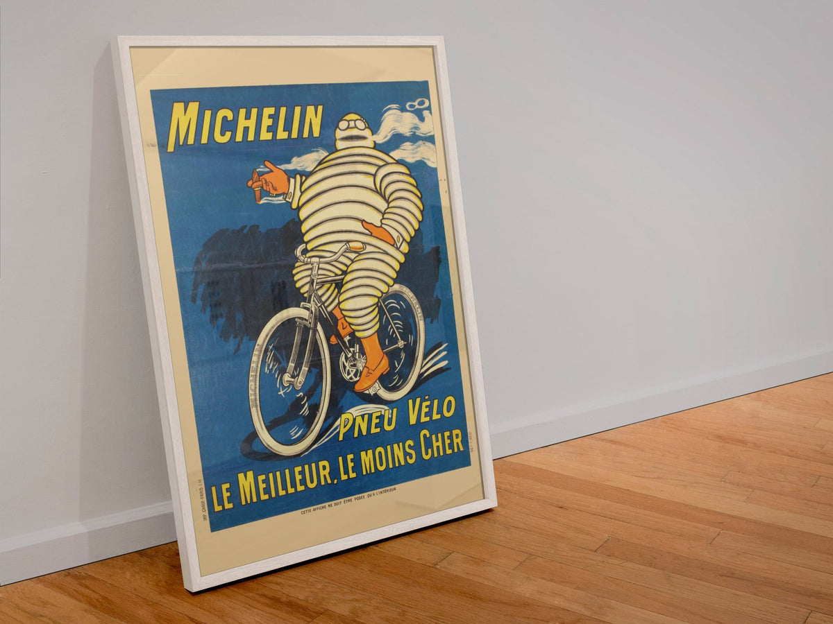 Michelin Pneu Velo Bibendum poster in a white frame leaning against a wall