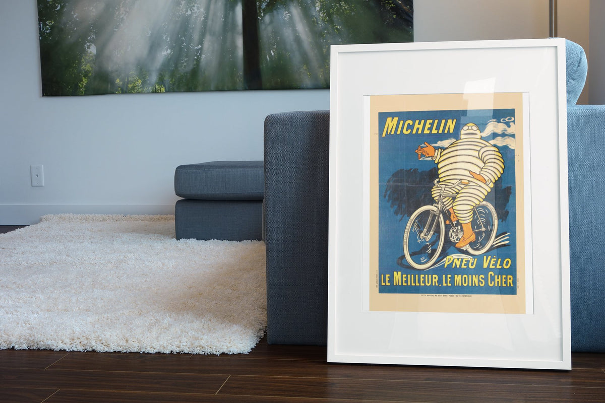 Michelin Pneu Velo Bibendum poster leaning beside a blue sofa