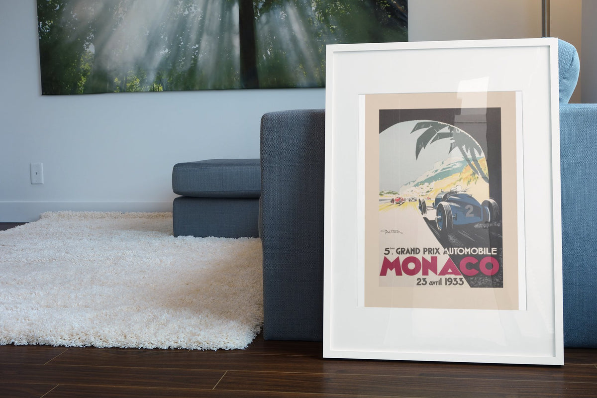 Monaco Grand Prix 1933 poster in a white frame leaning beside a blue sofa