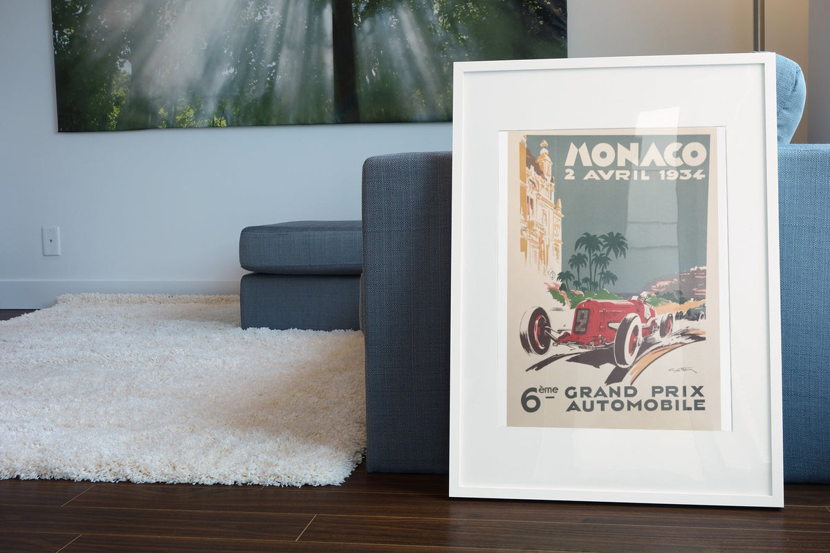 Monaco Grand Prix 1934 poster in a white frame leaning beside a blue sofa
