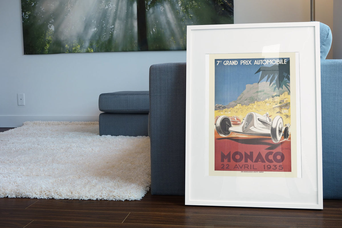 Monaco Grand Prix 1935 poster in a white frame leaning beside a blue sofa