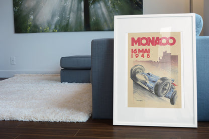 Monaco Grand Prix 1948 poster in a white frame leaning beside a blue sofa