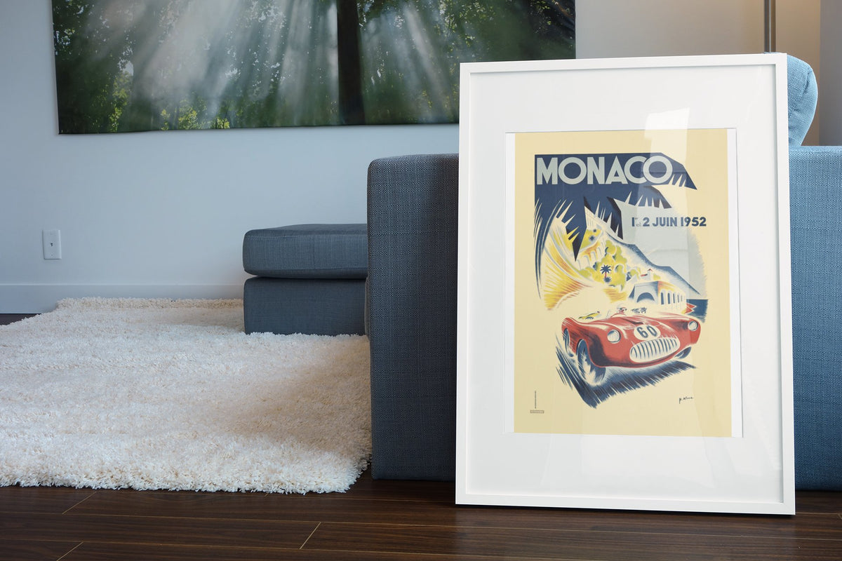 Monaco Grand Prix 1952 poster in a white frame leaning beside a blue sofa