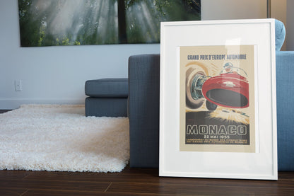 Monaco Grand Prix 1955 poster in a white frame leaning beside a blue sofa