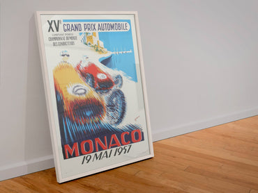 Monaco Grand Prix 1957 poster in a white frame leaning against a wall