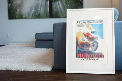 Monaco Grand Prix 1957 poster in a white frame leaning beside a blue sofa