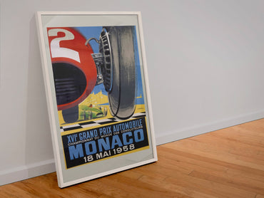 Monaco Grand Prix 1958 poster in a white frame leaning against a wall