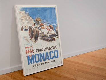 Monaco Grand Prix 1963 poster in a white frame leaning against a wall
