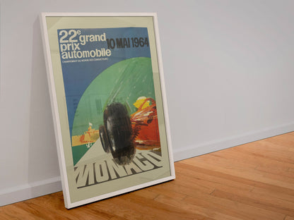 Monaco Grand Prix 1964 poster in a white frame leaning against a wall