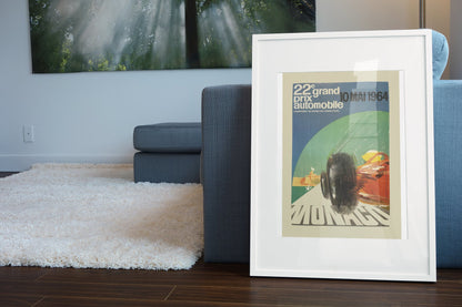 Monaco Grand Prix 1964 poster in a white frame leaning beside a blue sofa