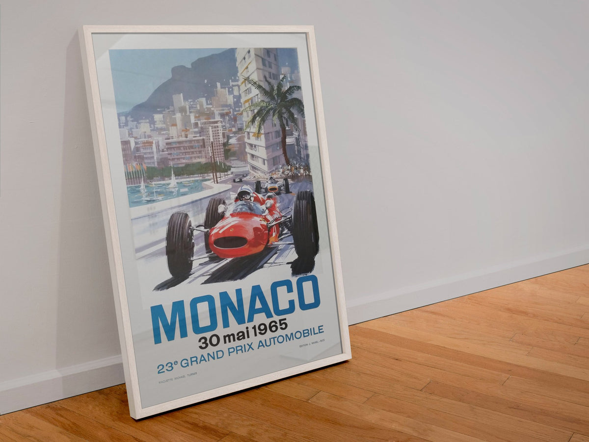 Monaco Grand Prix 1965 poster in a white frame leaning against a wall