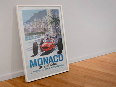Monaco Grand Prix 1965 poster in a white frame leaning against a wall