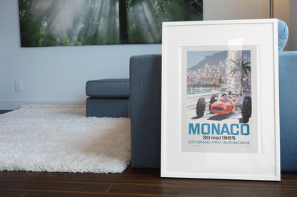 Monaco Grand Prix 1965 poster in a white frame leaning beside a blue sofa
