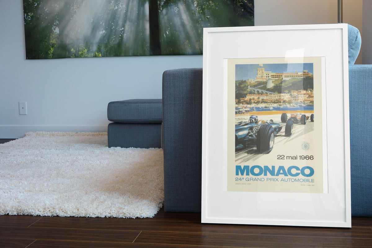 Monaco Grand Prix 1966 poster in a white frame leaning beside a blue sofa