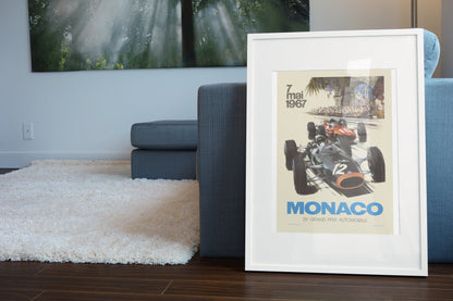 Monaco Grand Prix 1967 poster in a white frame leaning beside a blue sofa