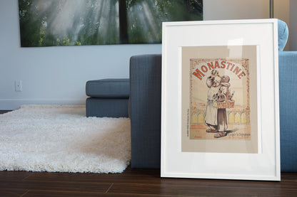 Monastine 1892 French liqueur poster in a white frame leaning beside a blue sofa