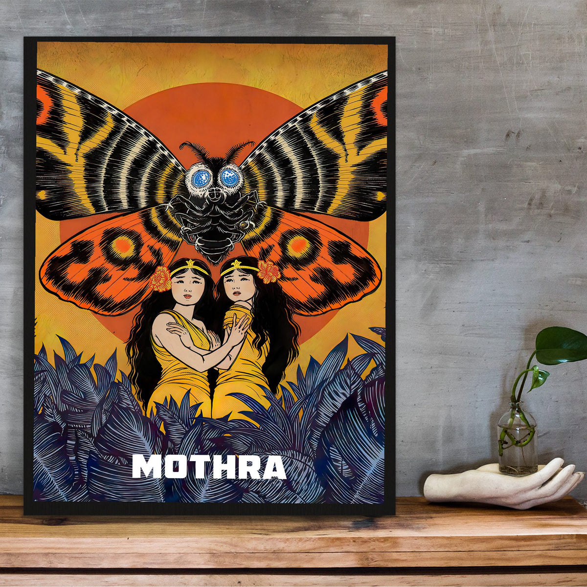Mothra (1961) Movie Illustrated Art poster in a black frame on a wooden shelf against concrete