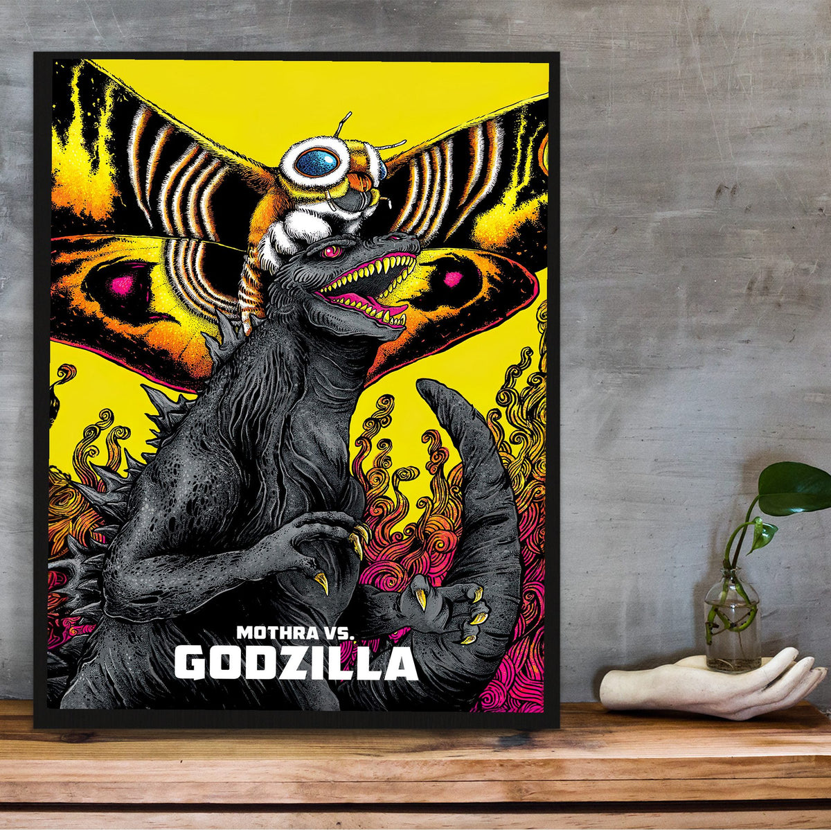 Mothra vs. Godzilla (1964) Movie Illustrated Art poster in a black frame on a wooden shelf against concrete