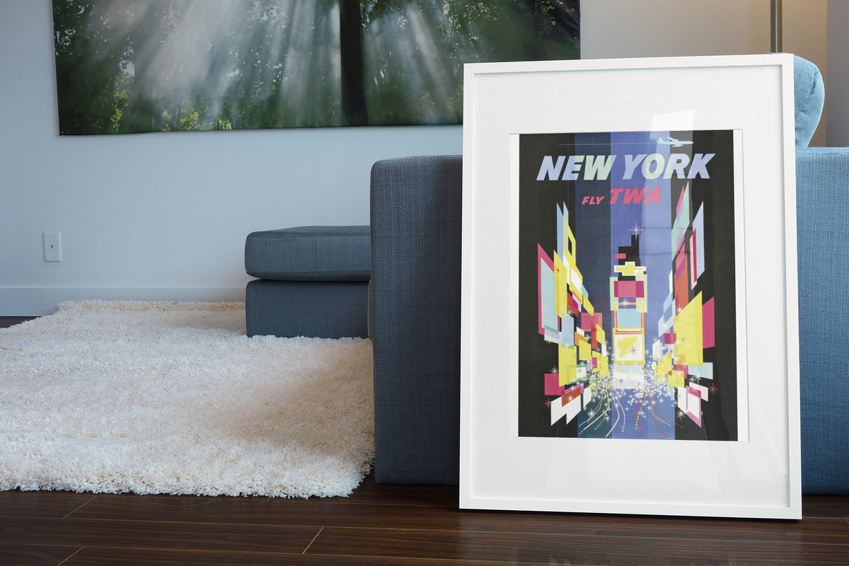 New York Times Square Fly TWA poster leaning beside a blue sofa