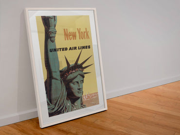 New York United Air Lines Statue of Liberty poster in a white frame leaning against a wall