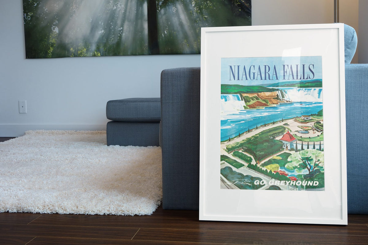 Niagara Falls Go Greyhound poster leaning beside a blue sofa