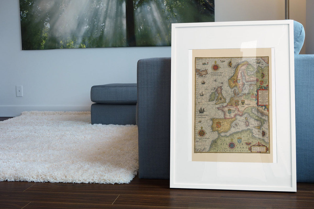 Northern Europe 1580s Sea Chart print in a white frame beside a blue sofa
