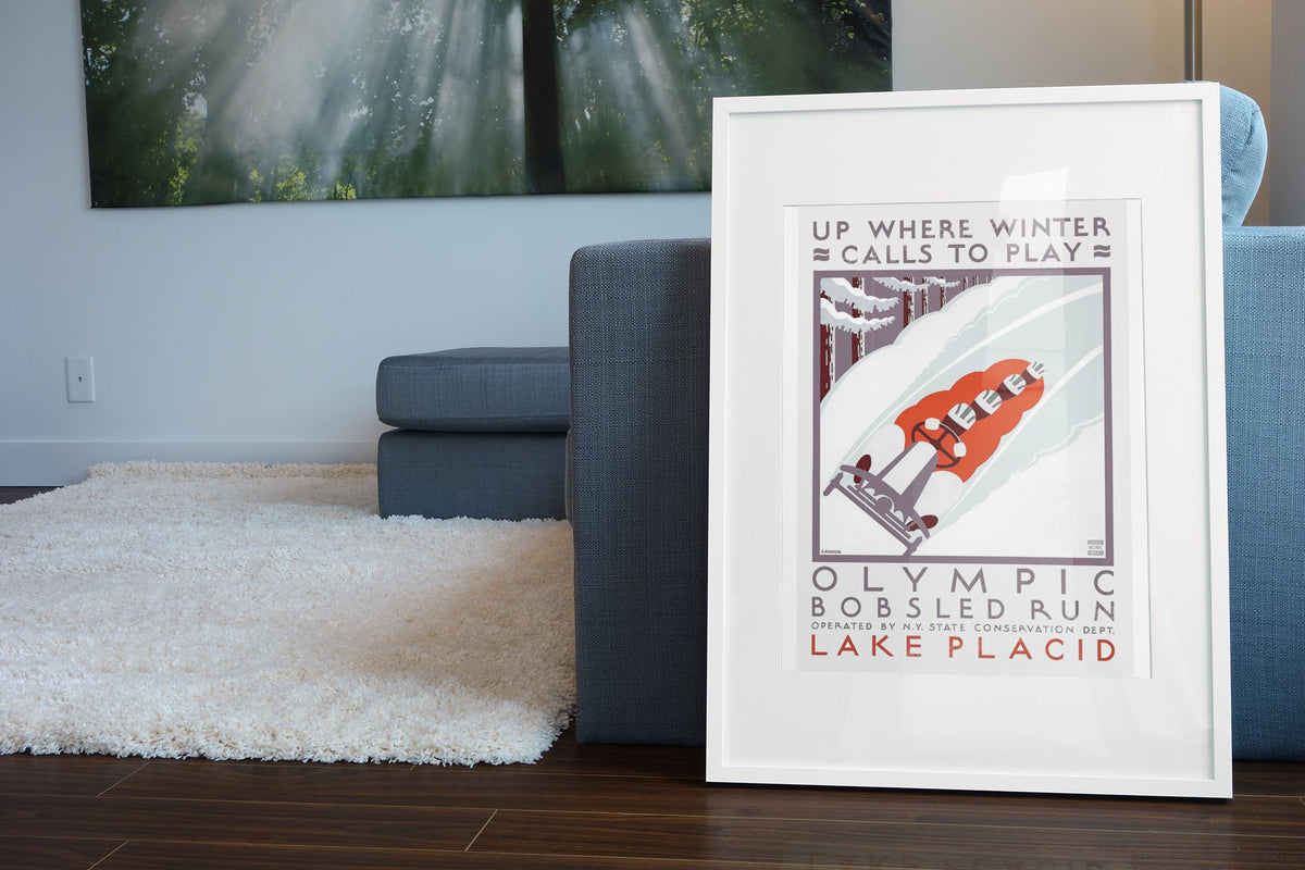 Olympic Bobsled Run Lake Placid poster leaning beside a blue sofa